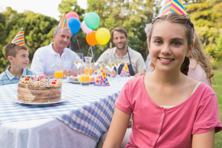 Little girl smiling at camera at her birthday party outside at picnic table の写真素材