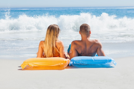Cute couple in swimsuit sunbathing together on the beachの写真素材