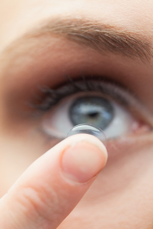 Extreme close up on cute model applying contact lens on her blue eyesの写真素材