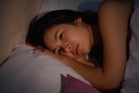 Young asian woman suffering from insomnia at home in bedroomの写真素材