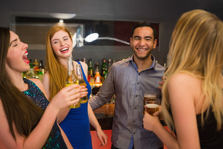 Laughing friends drinking beers and chatting in the nightclub