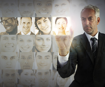Stern businessman choosing future employees on digital interfacesの写真素材