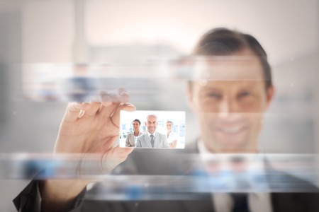 Pleased businessman presenting a picture of a business team on digital screenの写真素材