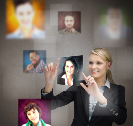 Smiling blonde businesswoman adjusting a picture on digital screenの写真素材