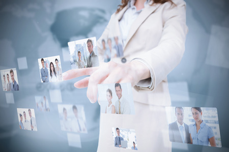 Stylish businesswoman presenting coworkers pictures on digital interfaceの写真素材