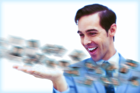 Amused businessman looking at a picture stream on white backgroundの写真素材