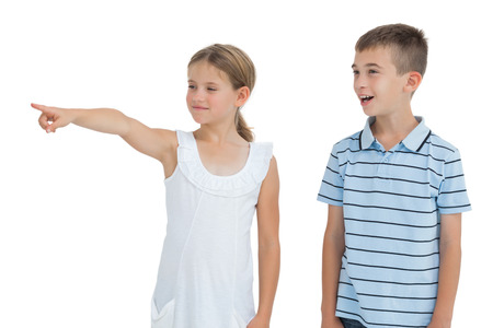 Young girl showing something to her brother while posing on white backgroundの写真素材