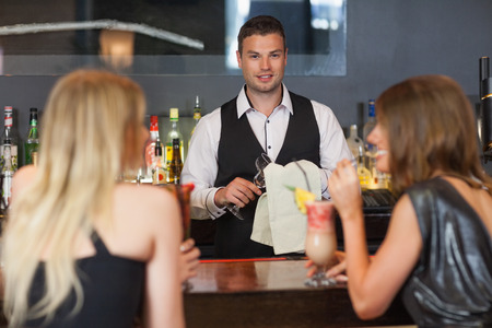 Handsome bartender working while gorgeous women talking on the counter in a classy barの写真素材
