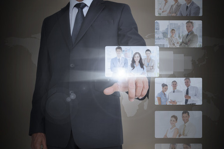 Classy businessman selecting digital interface of coworkersの写真素材