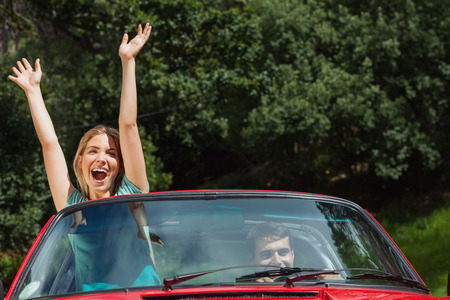 Happy couple having fun in their red cabriolet on a sunny dayの写真素材