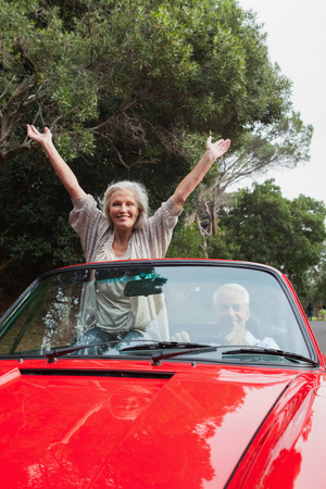 Smiling mature couple having a ride together in red convertibleの写真素材