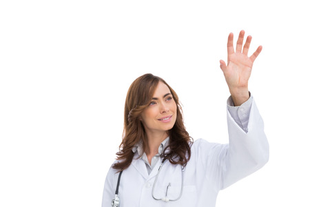 Brunette doctor reaching for something in the air on white backgroundの写真素材