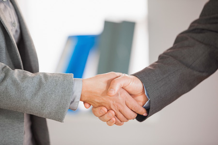 A businessman and a businesswoman having a handshake in an officeの写真素材