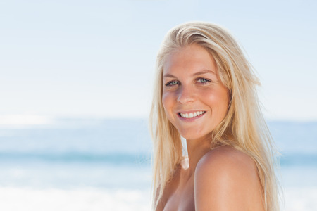 Close up view of blonde woman smiling at camera against oceanの写真素材