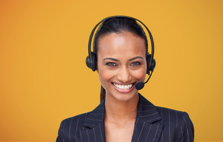 Attractive businesswoman smiling at camera on orange backgroundの写真素材