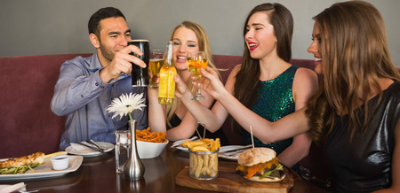 Friends having dinner together and clinking glasses in restaurant