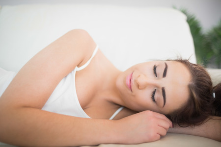 Peaceful young woman sleeping on a couch in the living roomの写真素材