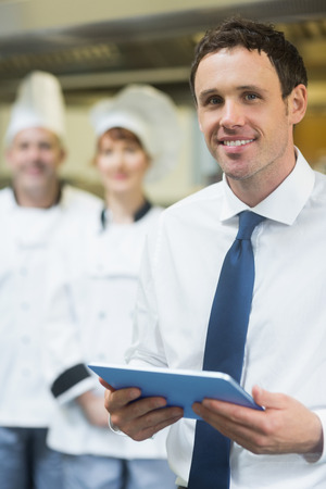 Young restaurant manager holding his tablet  smiling at the camera 