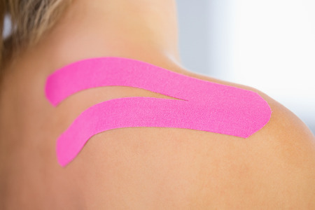 Close up of patients shoulder with applied kinesio tape in bright officeの写真素材