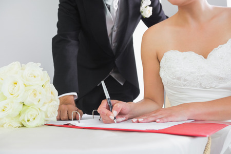 Mid section of a young couple signing wedding contract sitting at deskの写真素材