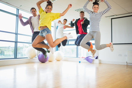 Group portrait of young fit people jumping in bright exercise roomの写真素材
