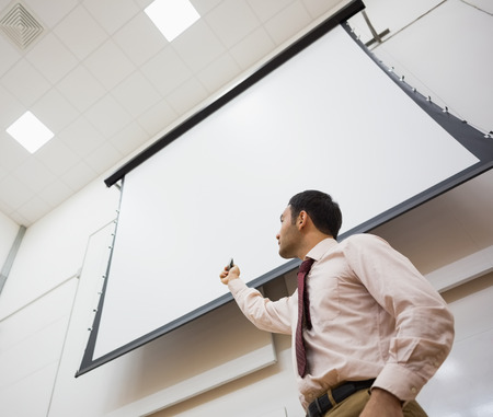 Low angle view of an elegant male teacher with projection screen in the lecture hall