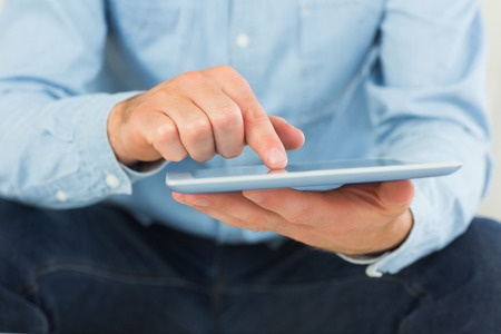 Casual man using and holding tablet in bright living room