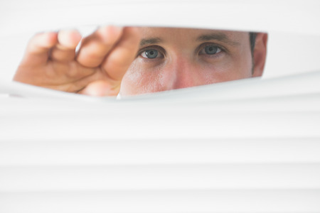 Male blue eyes observing through roller blind