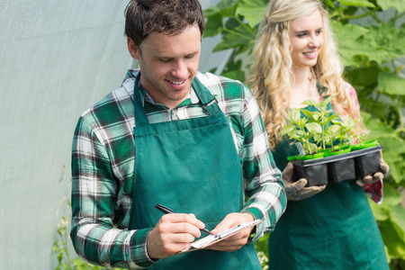 Smiling man using a clipboard in a green houseの写真素材