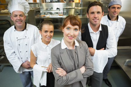 Cute female manager posing with the staff in a modern kitchen