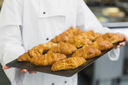 Baker presenting some croissants on a baking trayの写真素材
