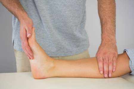 Physiotherapist checking patients foot in bright officeの写真素材