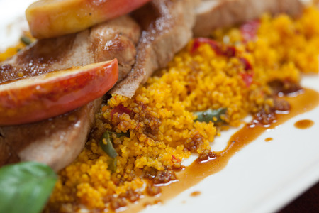 Close up of couscous with meat and apple on white plateの写真素材