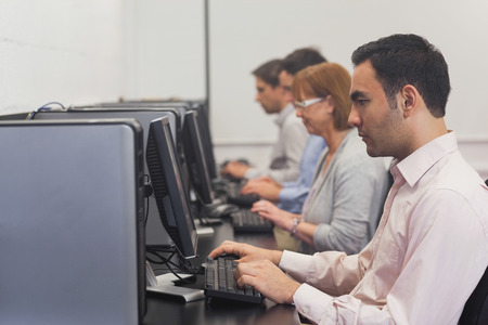Mature students sitting in computer class working on computers