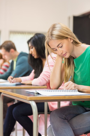 Side view of a group of young students writing notes in the classroomの写真素材