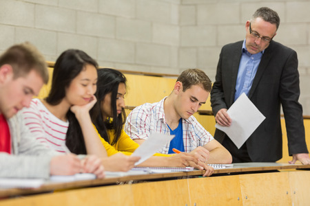 Elegant teacher with students writing notes at the college lecture hallの写真素材