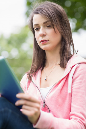 Close-up of a serious young college girl using tablet PC outdoorsの写真素材