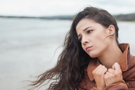 Close up of a cute thoughtful young woman on the beachの写真素材