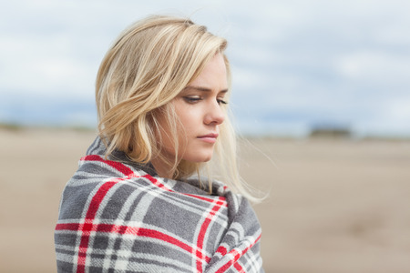 Close up side view of a young woman covered with blanket at the beach