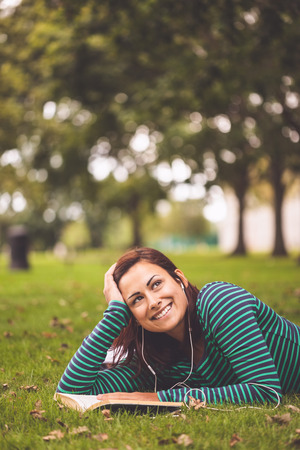 Smiling casual student lying on grass looking up on campus at collegeの写真素材