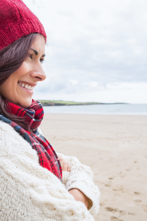 Close up side view of a young woman in knitted hat and pullover smiling at the beachの写真素材
