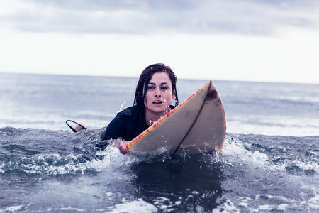 Portrait of a young woman swimming over surfboard in the water at beach