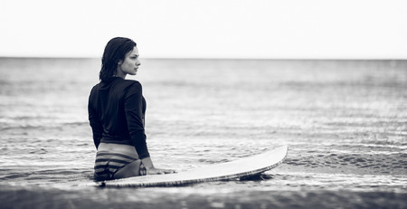 Rear view of a woman with surfboard in the water at beachの写真素材