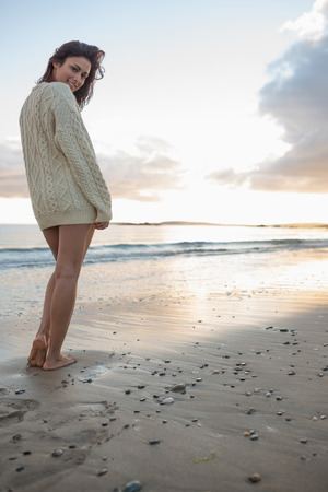 Full length portrait of a young woman in sweater standing on the beachの写真素材