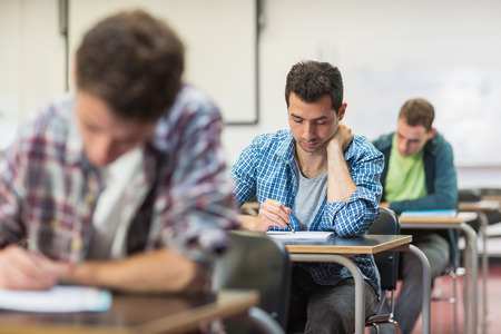 Group of young students writing notes in the classroomの写真素材