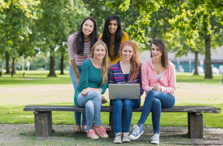 Group portrait of young college girls with laptop in the parkの写真素材