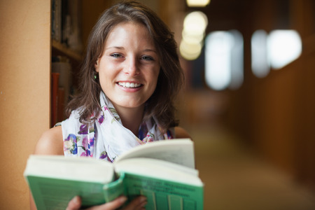 Close-up portrait of a smiling female student in the libraryの写真素材