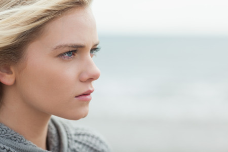 Close up side view of a serious cute young woman on the beach