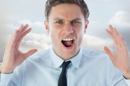 Angry businessman shouting against clouds in a roomの写真素材