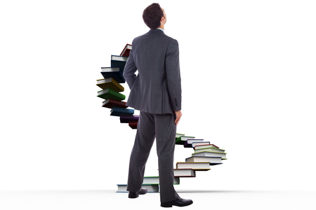 Businessman standing with hand on hip against steps made out of booksの写真素材